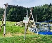 Riesenschaukel mit Trampolin und Wald in Hintergrund