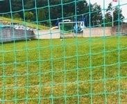 Blick auf den Fußballplatz durch das Netz der Fußballtore