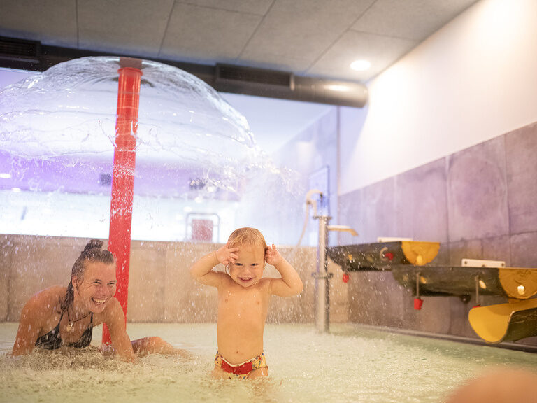 Mutter spielt mit Kind im Babypool