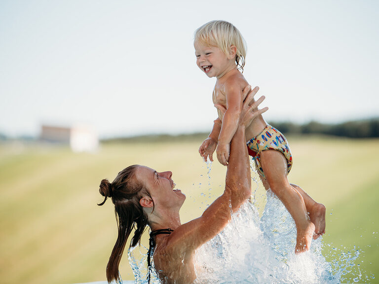 Mutter hebt Kind im Wasser nach oben