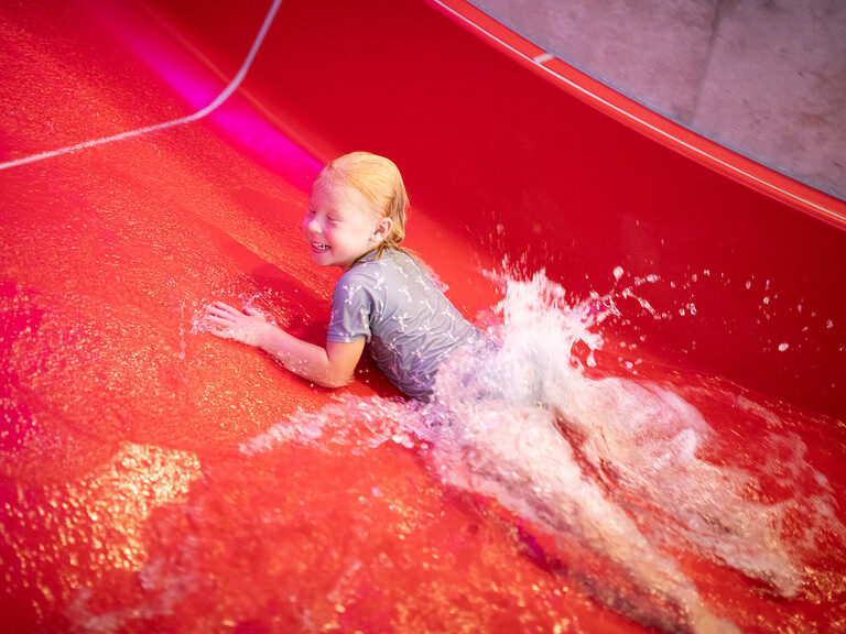 Kind rutscht rückwärts die Wasserrutsche runter