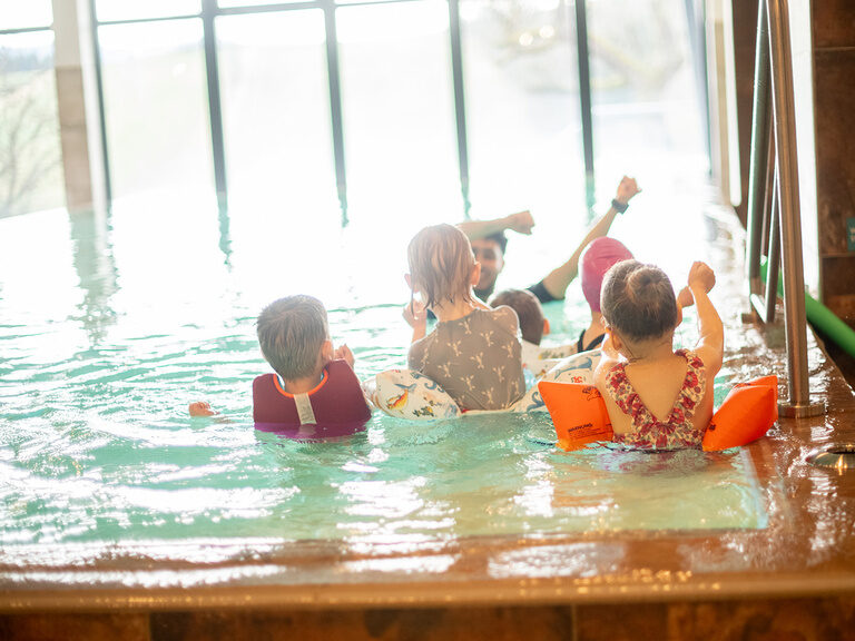 Kinder mit Kinderbetreuer beim Schwimmkurs im Wasser