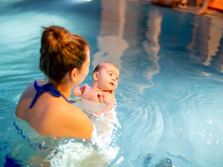 Mama mit Baby im Arm im Wasser