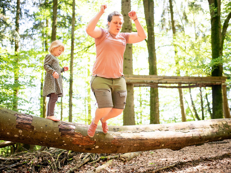 Frau springt von umgestürzten Baum während das Kind zu sieht