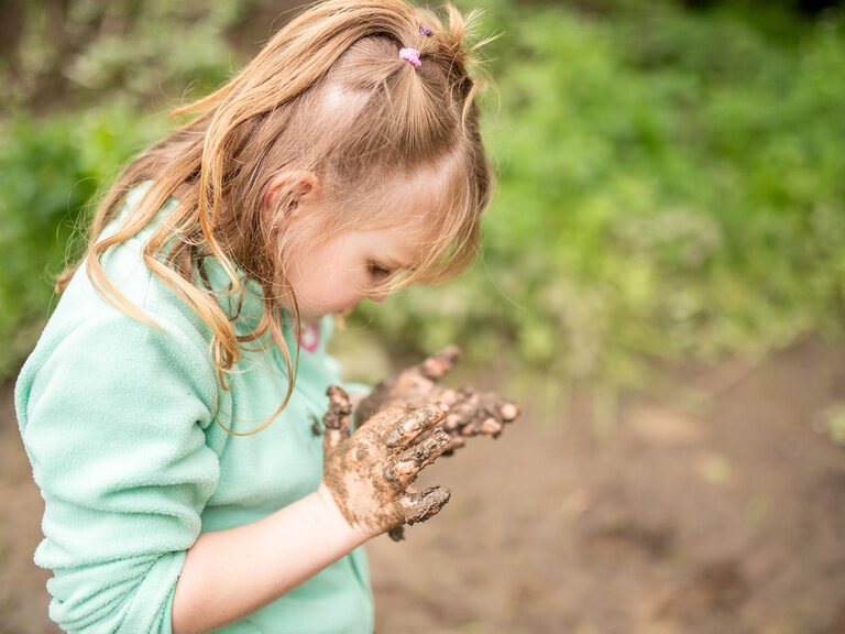 Mädchen untersucht Matsch in den Händen