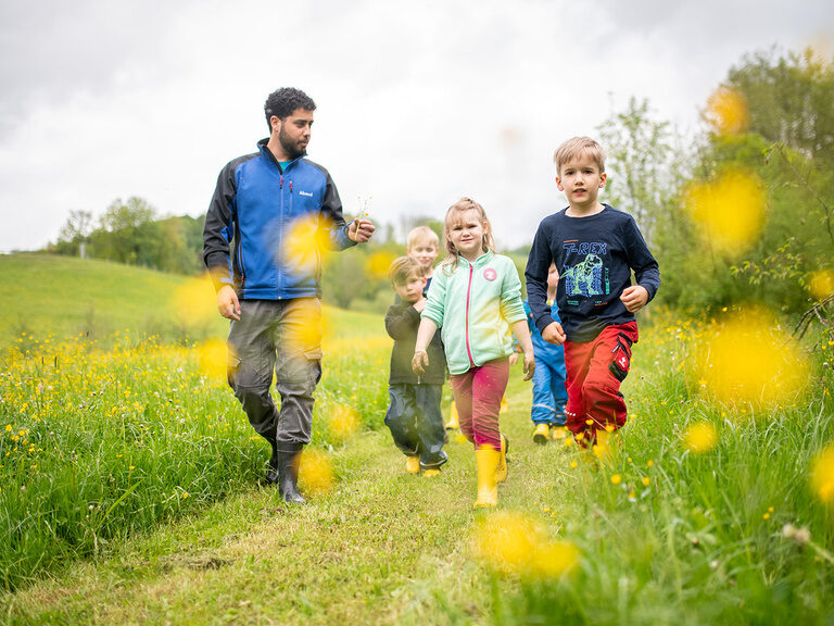 Kinderbetreuer geht mit Kindern über Wiese