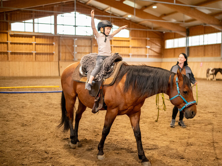 Kind auf Pferd in der Reithalle