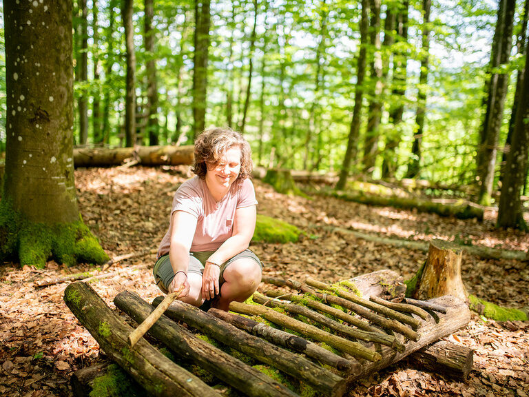 Frau spielt im Wald mit einem Baum Xylophon