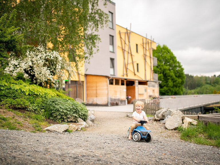 Kind auf Bobbycar vor der Hotelterrasse