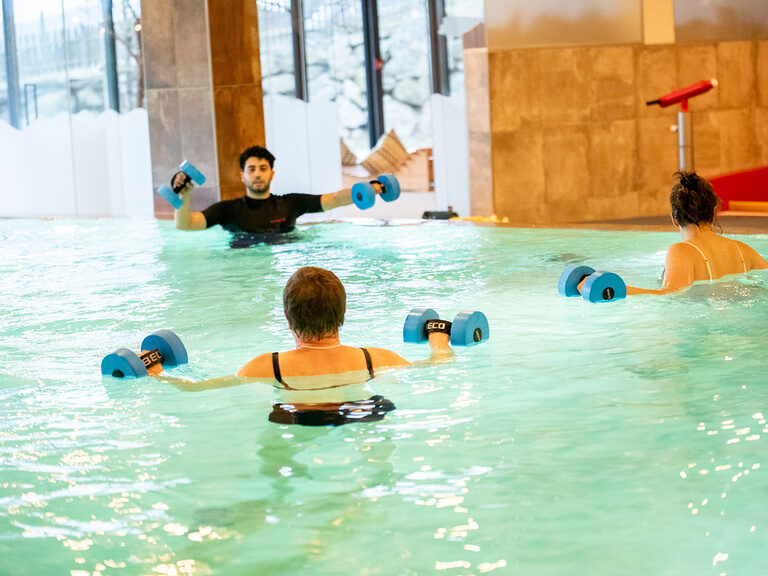 2 Frauen machen einem Mann Bewegungen im Wasser nach