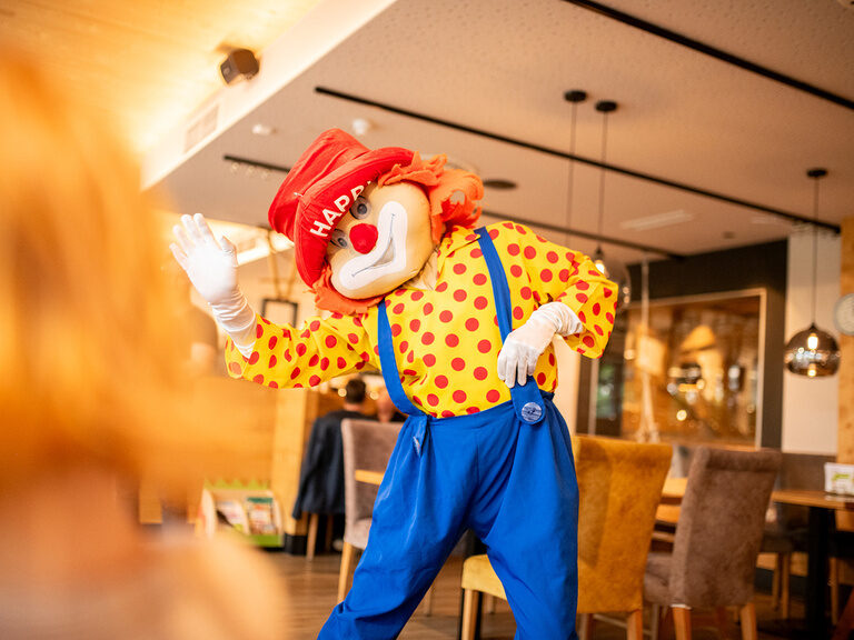 Clown winkt Kindern im Restaurant