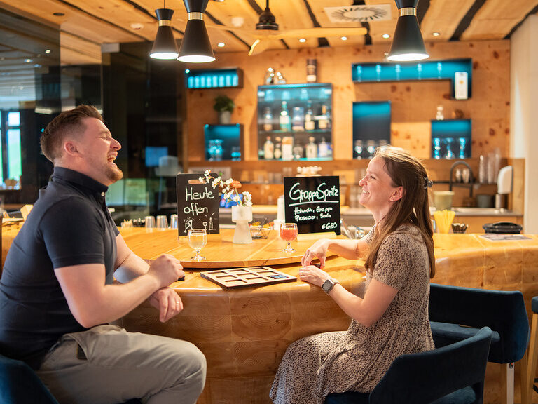 Mann und Frau sitzen an der Bar, lachen und spielen ein Spiel gemeinsam