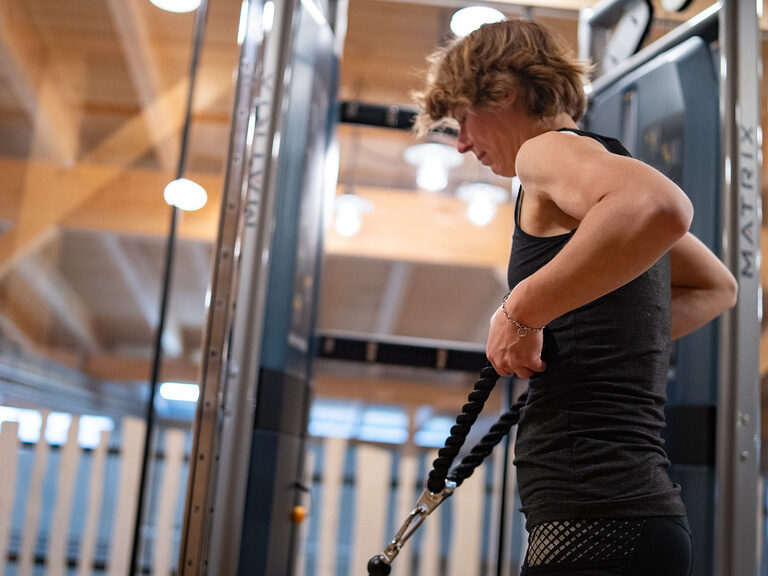 Frau im Fitness Studio macht Übung am Kabelturm