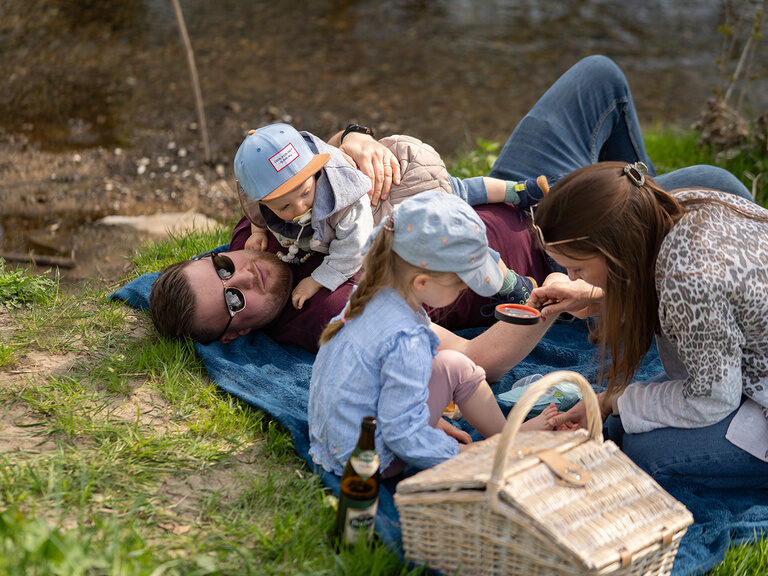 Eltern und Kinder liegen auf einer Picknickdecke in der Natur