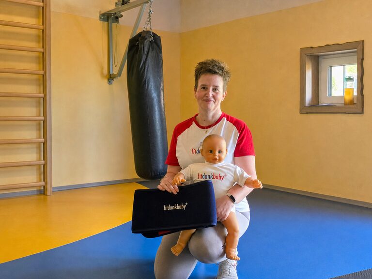 Frau mit Puppe und FitDankBaby Gurt